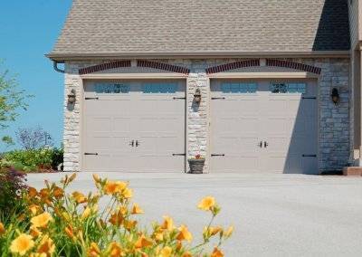 stamped carriage garage door with flowers in the yard