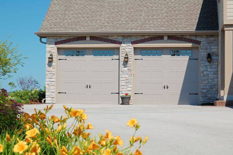 stamped carriage garage door with flowers in the yard